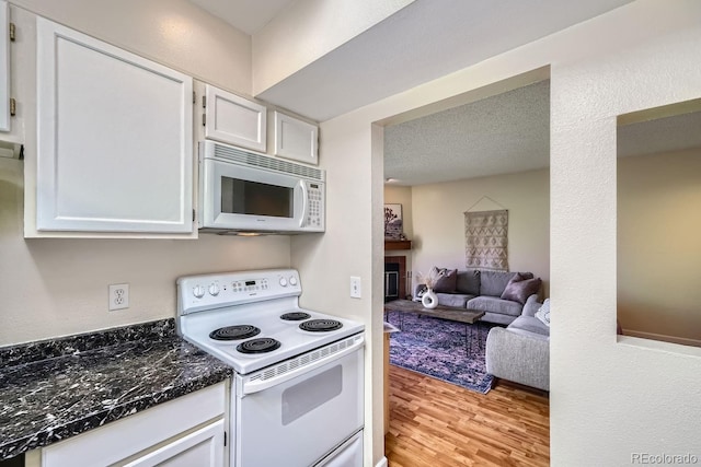3050 W 32nd Ave Unit 202C, Denver, CO 80211 - kitchen with white appliances, light wood-type flooring, a glass covered fireplace, white cabinetry, and open floor plan