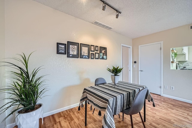3050 W 32nd Ave Unit 202C, Denver, CO 80211 - dining area featuring rail lighting, wood finished floors, a textured ceiling, and baseboards