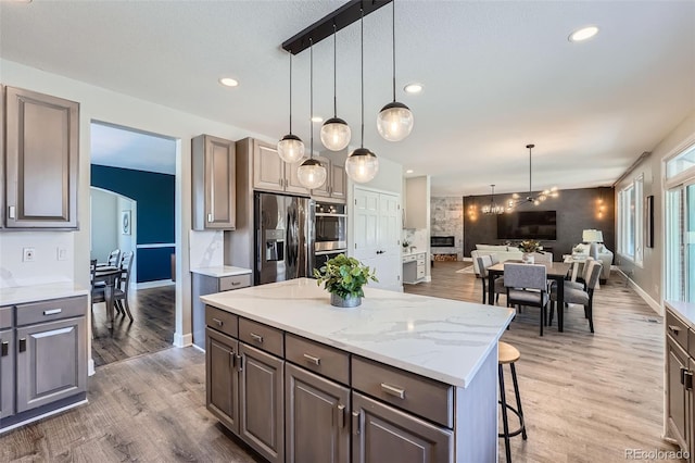 kitchen featuring a kitchen bar, decorative light fixtures, appliances with stainless steel finishes, a kitchen island, and hardwood / wood-style floors