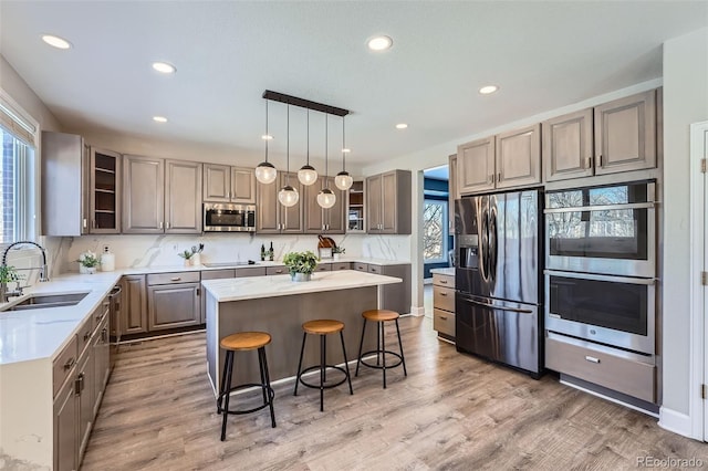 kitchen featuring a kitchen bar, sink, a center island, appliances with stainless steel finishes, and hardwood / wood-style flooring