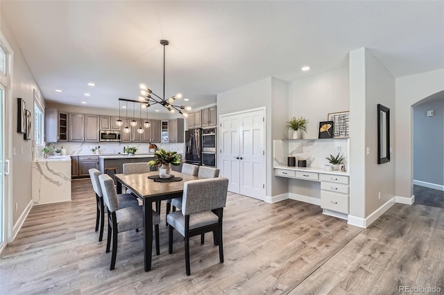 dining area featuring light wood-style flooring, arched walkways, baseboards, and recessed lighting