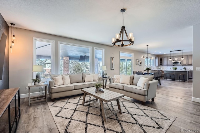 living room with a chandelier, light hardwood / wood-style floors, and a textured ceiling