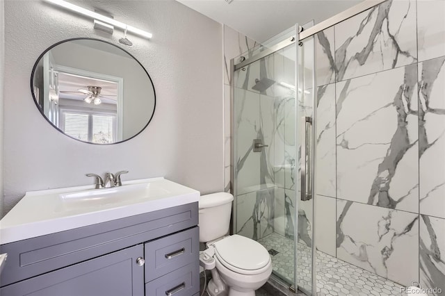 bathroom featuring toilet, a textured wall, a marble finish shower, and vanity