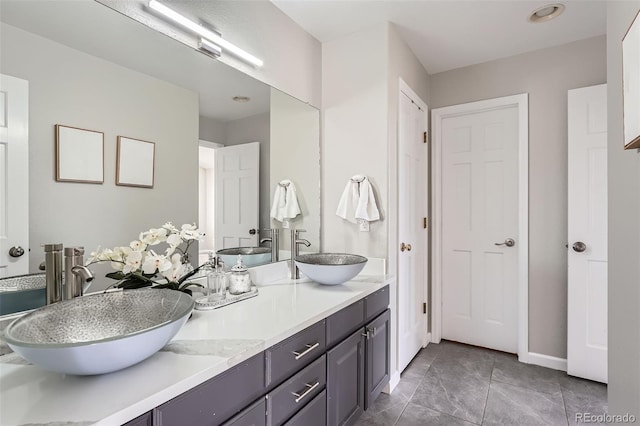 full bath with double vanity, baseboards, and a sink