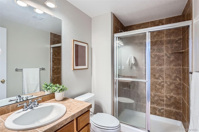 bathroom featuring vanity, a shower with door, and toilet