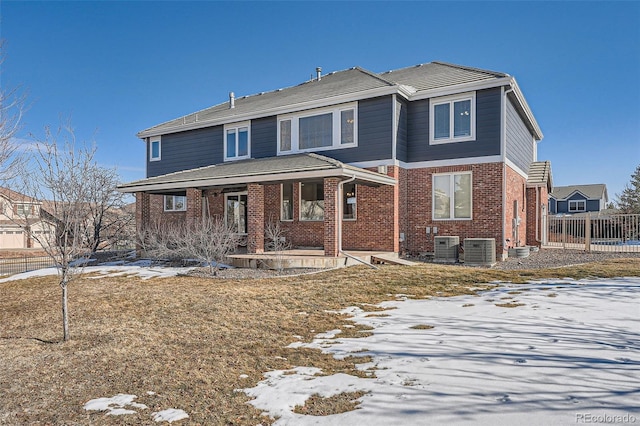 traditional-style home featuring covered porch, brick siding, central AC unit, and fence