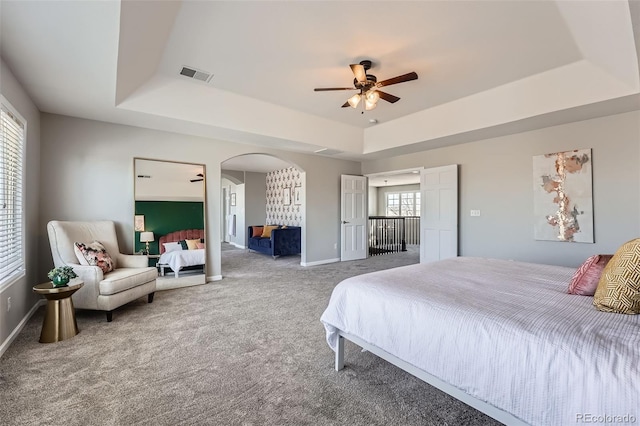 bedroom featuring a raised ceiling, ceiling fan, and carpet flooring