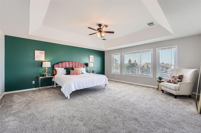 carpeted bedroom featuring ceiling fan and a raised ceiling