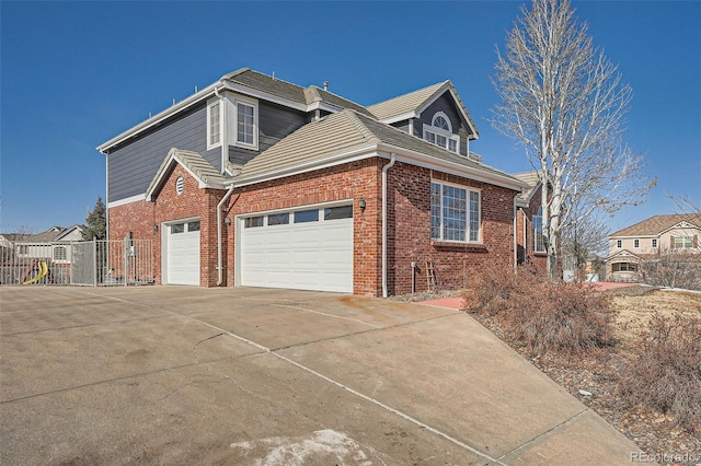 view of property exterior with concrete driveway, brick siding, and fence