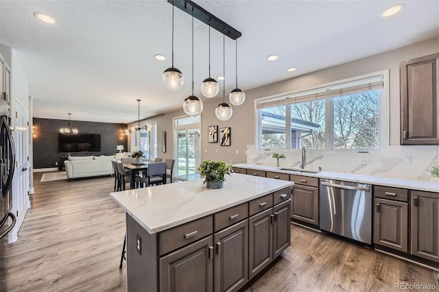 kitchen with a sink, wood finished floors, recessed lighting, open floor plan, and stainless steel dishwasher