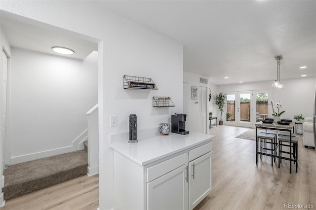 2232 Coronado Pkwy Unit B, Denver, CO 80229 - kitchen featuring light wood-style flooring, open floor plan, white cabinets, light countertops, and decorative light fixtures