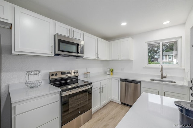 2232 Coronado Pkwy Unit B, Denver, CO 80229 - kitchen with appliances with stainless steel finishes, light wood finished floors, light countertops, white cabinetry, and recessed lighting