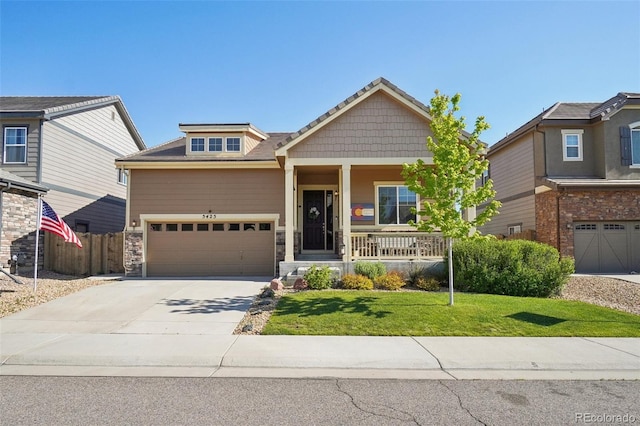craftsman-style house with driveway, covered porch, an attached garage, and stone siding