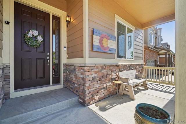 doorway to property with covered porch and stone siding