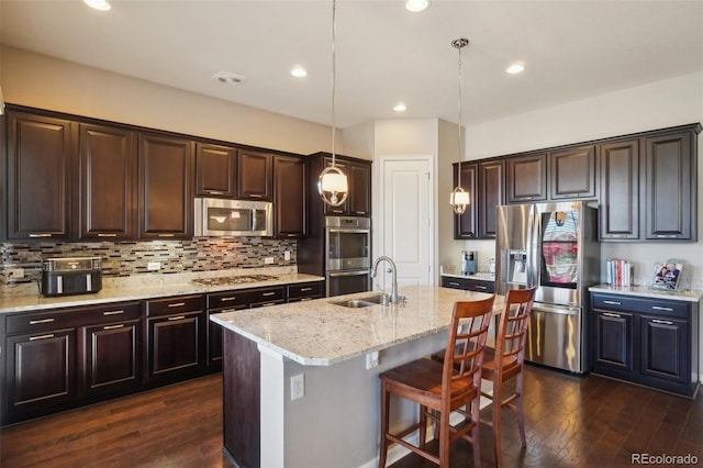 kitchen featuring stainless steel appliances, a sink, dark wood finished floors, dark brown cabinets, and recessed lighting