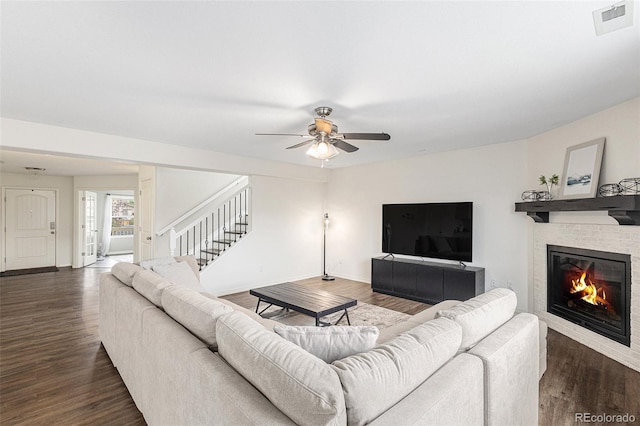 living room with a fireplace, dark hardwood / wood-style floors, and ceiling fan