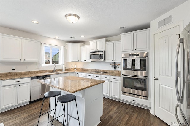 kitchen featuring white cabinetry, appliances with stainless steel finishes, a center island, and sink