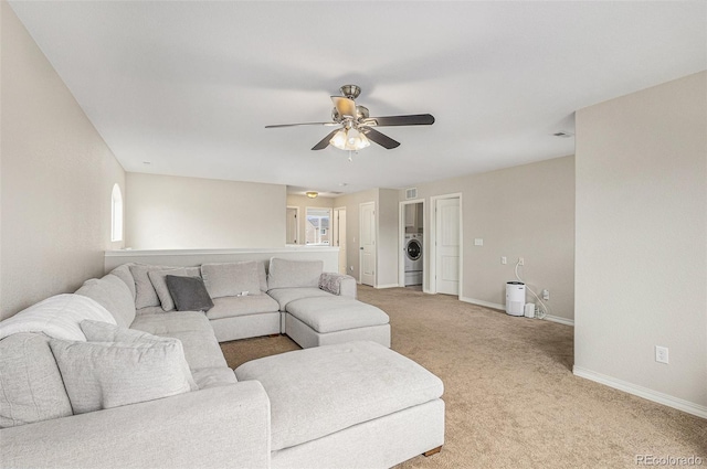 carpeted living room with washer / dryer and ceiling fan