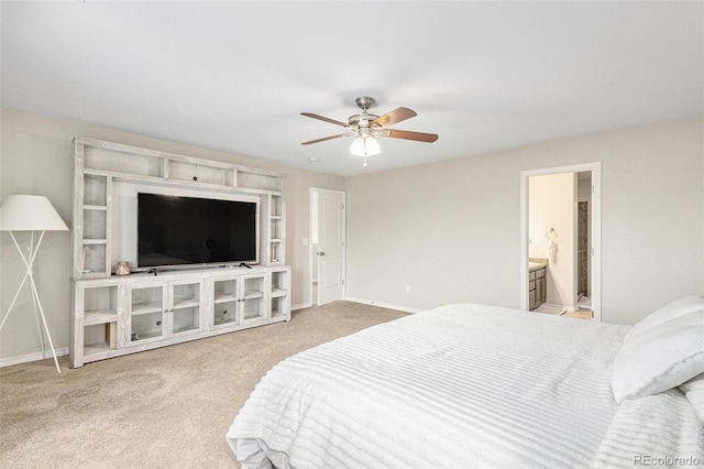 bedroom featuring ceiling fan, light colored carpet, and ensuite bath