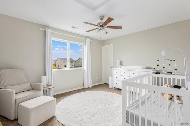 carpeted bedroom featuring a nursery area and ceiling fan