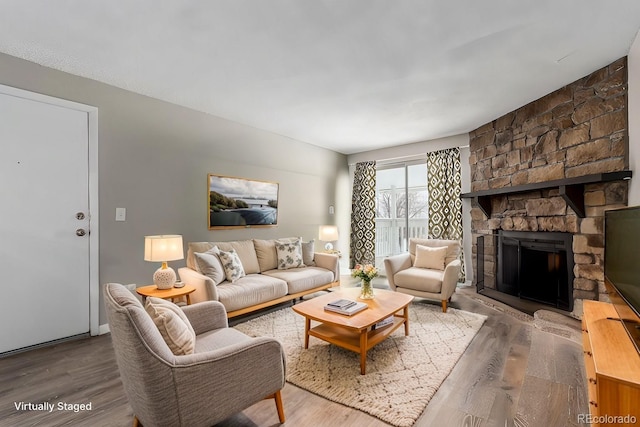 living room with hardwood / wood-style flooring and a stone fireplace