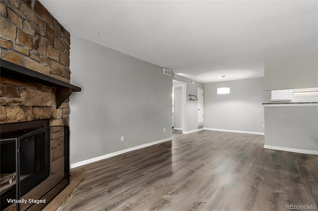 unfurnished living room featuring hardwood / wood-style floors and a stone fireplace