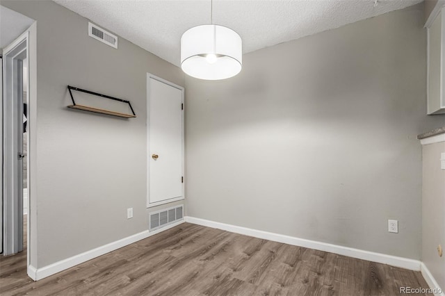 empty room with light hardwood / wood-style floors and a textured ceiling