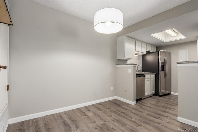 kitchen with light hardwood / wood-style flooring, white cabinets, a textured ceiling, and appliances with stainless steel finishes