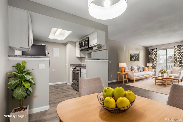 dining space with a skylight and hardwood / wood-style floors