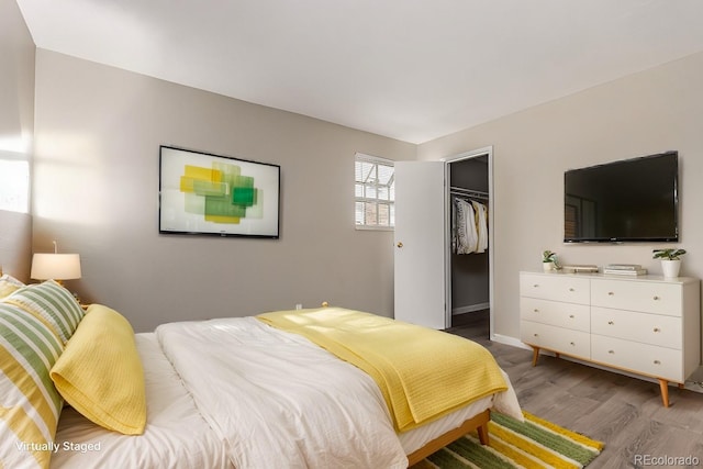 bedroom with hardwood / wood-style floors, a spacious closet, and a closet