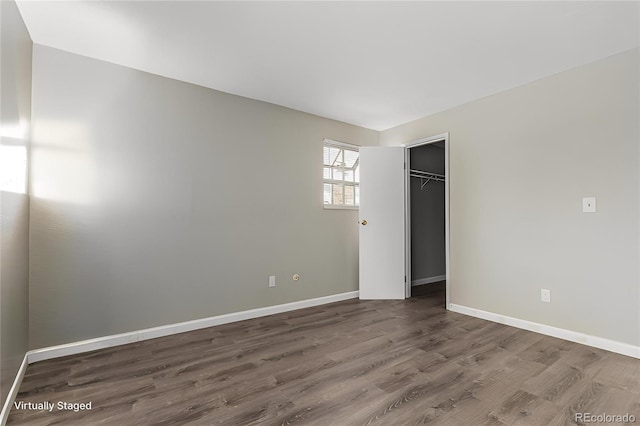 unfurnished bedroom featuring a walk in closet, a closet, and wood-type flooring