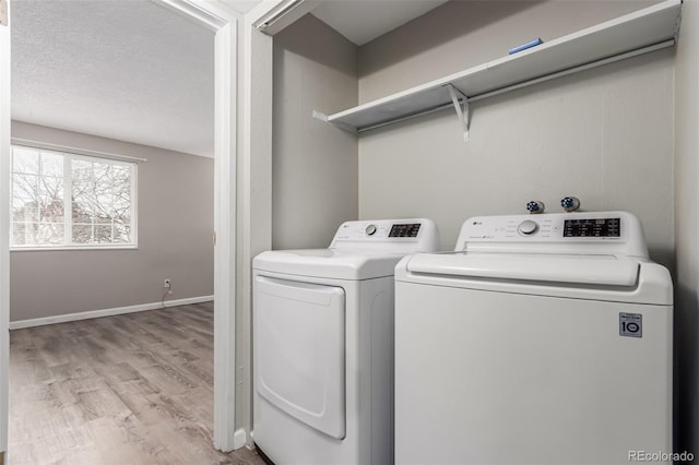 laundry room with washer and clothes dryer, light hardwood / wood-style floors, and a textured ceiling