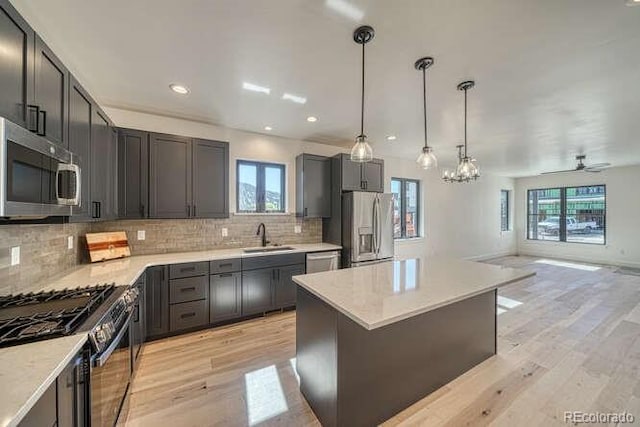136 Chase St, Salida, CO 81201 - kitchen with appliances with stainless steel finishes, backsplash, light wood finished floors, open floor plan, and pendant lighting