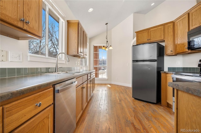 kitchen with vaulted ceiling, a notable chandelier, stainless steel appliances, and a wealth of natural light