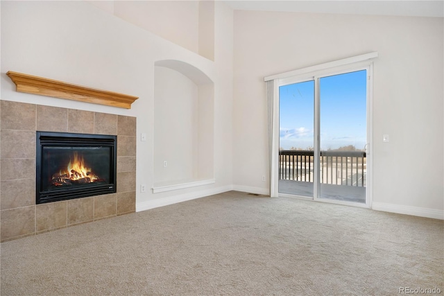 unfurnished living room with a fireplace, high vaulted ceiling, and carpet flooring