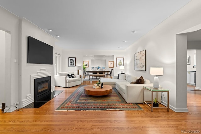 living room with wood finished floors, a fireplace with flush hearth, and baseboards