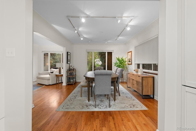 dining room with rail lighting and wood finished floors