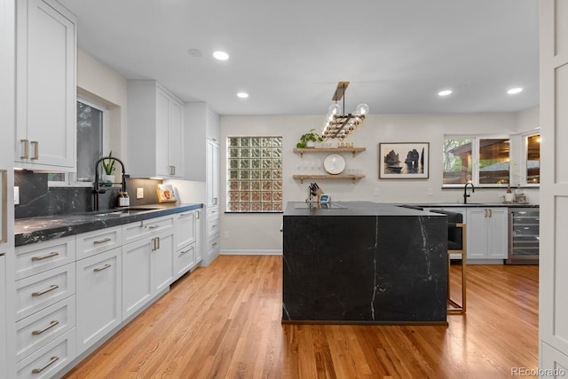 kitchen featuring wine cooler, a sink, white cabinetry, healthy amount of natural light, and recessed lighting
