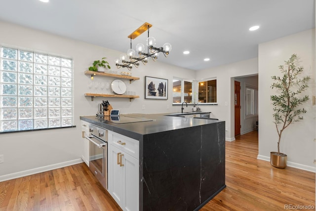 kitchen featuring dark countertops, oven, light wood-style floors, white cabinets, and recessed lighting