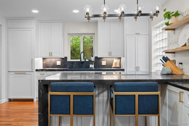 kitchen with open shelves, backsplash, white cabinets, dark stone countertops, and light wood-style floors