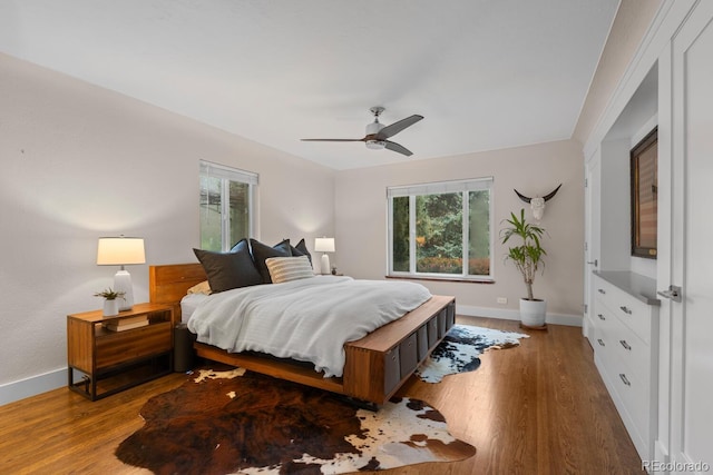 bedroom featuring baseboards, wood finished floors, and ceiling fan