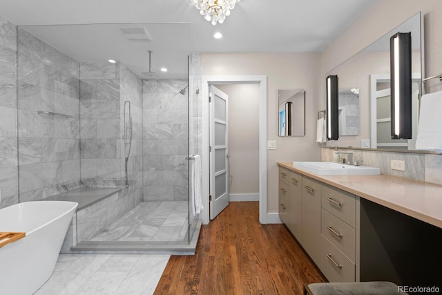 full bath featuring a tile shower, vanity, recessed lighting, a freestanding tub, and baseboards