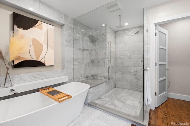 bathroom with a stall shower, a soaking tub, recessed lighting, and baseboards
