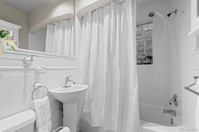 full bath with shower / bath combination with curtain, tile walls, toilet, and a sink