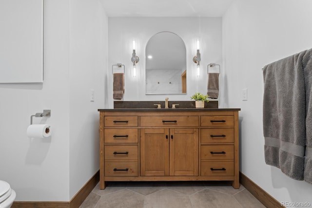 bathroom with baseboards, toilet, vanity, tile patterned flooring, and a shower