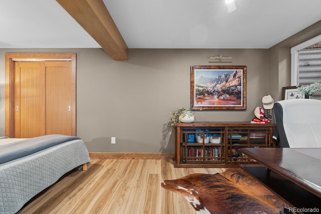 bedroom with wood finished floors, baseboards, and beam ceiling