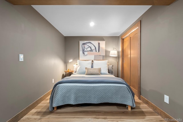 bedroom featuring baseboards, light wood-style floors, and a closet