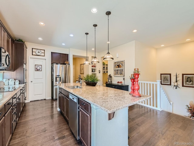 16658 Prospect Ln, Broomfield, CO 80023 - kitchen featuring appliances with stainless steel finishes, dark brown cabinets, dark wood finished floors, light stone countertops, and a kitchen bar