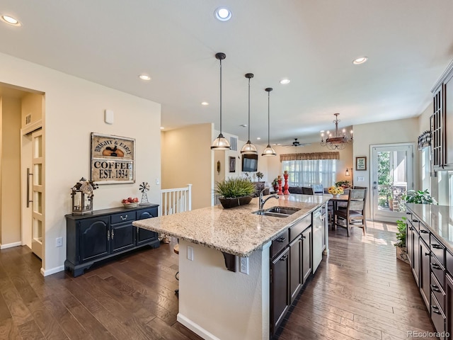 16658 Prospect Ln, Broomfield, CO 80023 - kitchen featuring dark wood finished floors, light stone countertops, a chandelier, stainless steel dishwasher, and a center island with sink