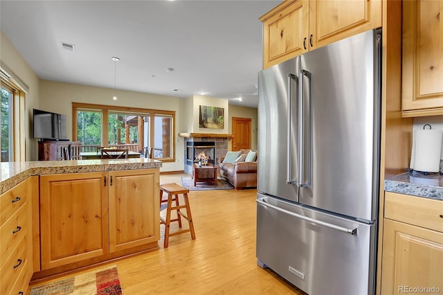 147 Forest Trl Unit 3, Winter Park, CO 80482 - kitchen featuring high end fridge, light wood finished floors, a tile fireplace, tile countertops, and a breakfast bar